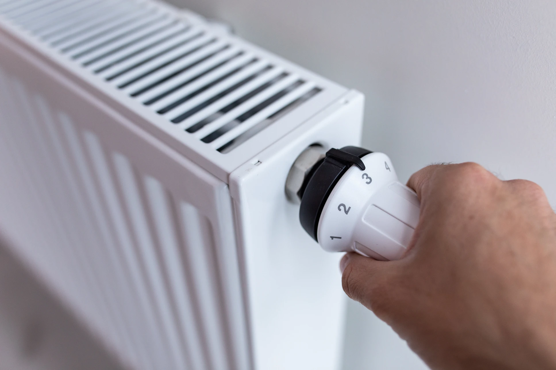 Intérieur résidentiel, main masculine ajustant un robinet thermostatique de radiateur à eau chaude