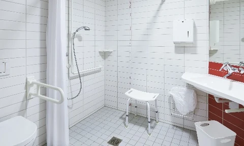 Salle de bain moderne minimaliste aux murs gris anthracite avec lavabo rectangulaire blanc suspendu, robinetterie chromée contemporaine, miroir sans cadre, étagère flottante noire avec accessoires de toilette et miroir grossissant sur bras articulé