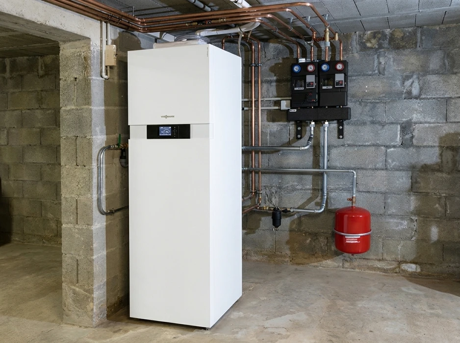 Sous-sol technique avec une pompe à chaleur géothermique **Viessmann Vitocal** (unité intérieure blanche), raccordée à un réseau de tuyauteries en cuivre et acier