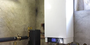 Intérieur résidentiel, technicien en combinaison bleue installant un radiateur blanc mural