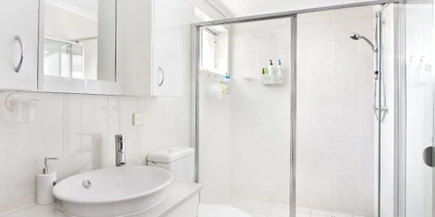 Toilettes murales suspendues dans un espace sanitaire moderne avec carrelage gris et mosaïque décorative