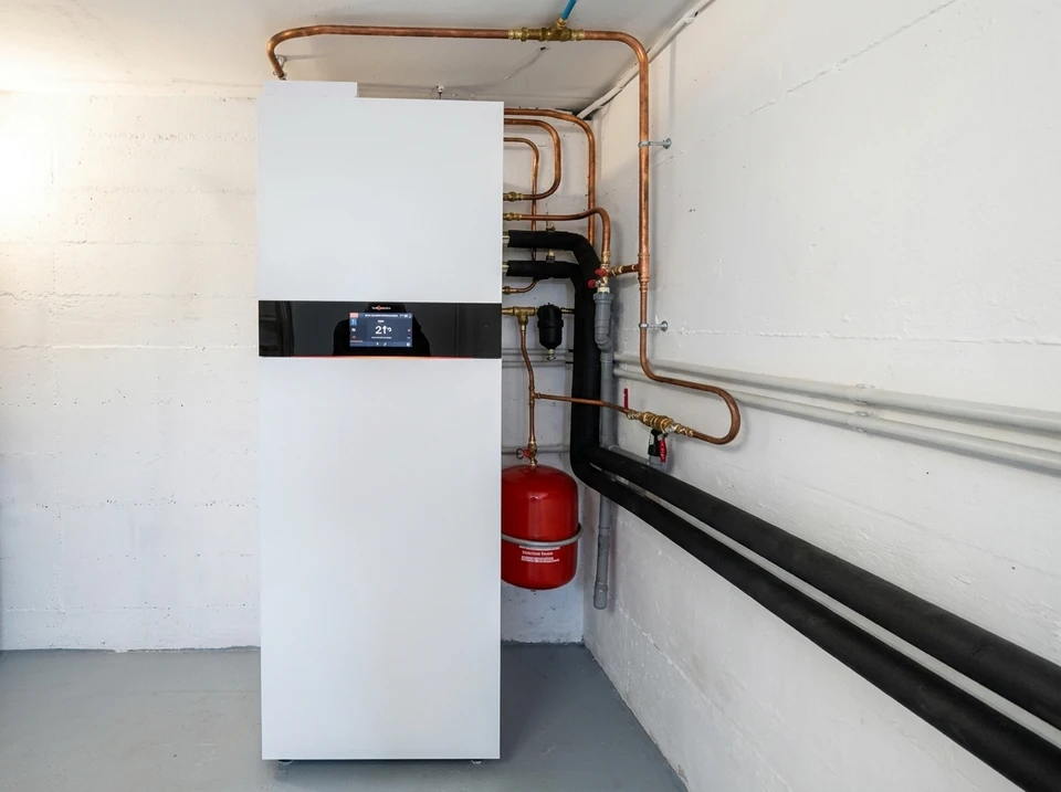Local technique moderne avec chaudière murale blanche, ballon de stockage cylindrique et réseau de distribution complexe