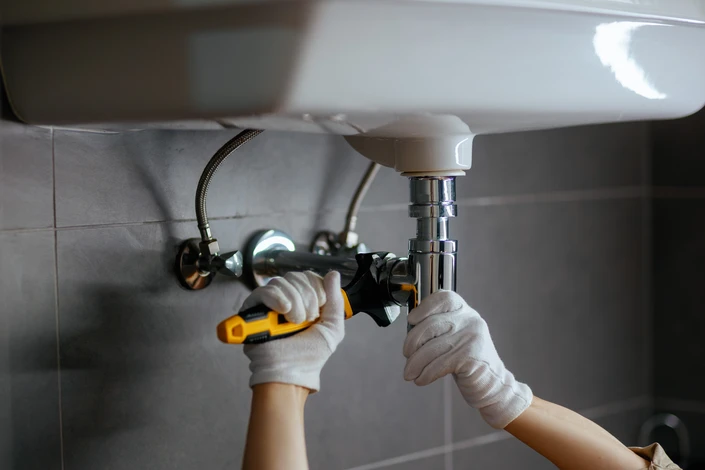 Homme en polo noir installant un équipement sanitaire dans salle de bain moderne
